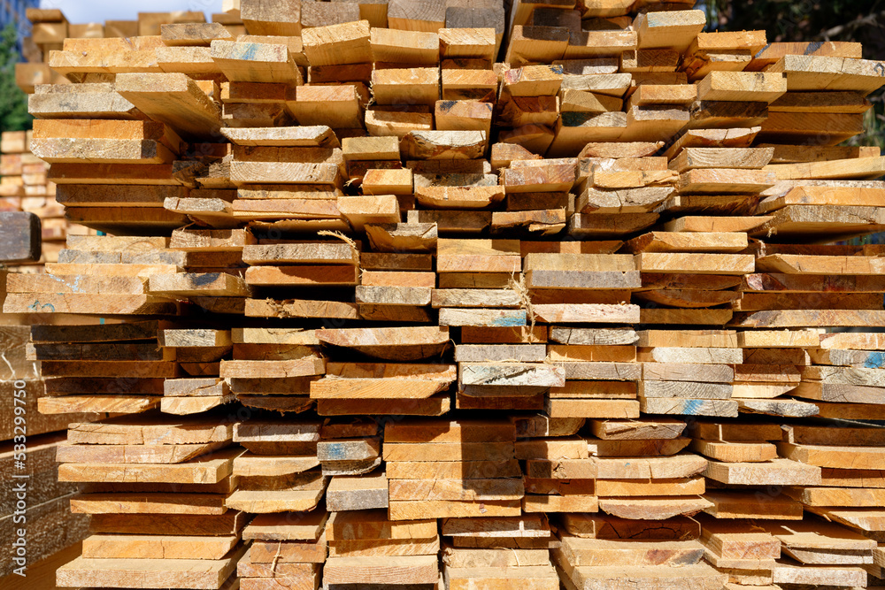 Blocks of pine sawn timber for the construction of roof houses and cottages stacked on the lumberyards site, ready for sale Blocks of pine sawn timber for the construction of roof houses and cottages stacked on the lumberyards site, ready for sale