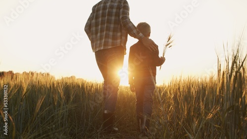 Obraz na plátne Farmer and his son in front of a sunset agricultural landscape