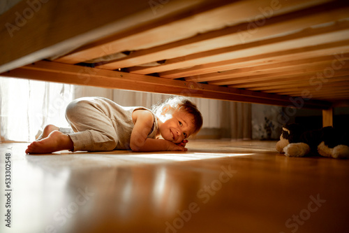 Smiling cute boy searching for stuffed toy animal under bed