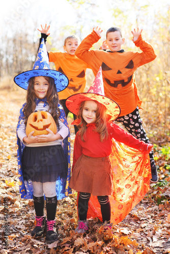 a group of children - boys and girls in carnival costumes of witches and with a pumpkin Jack in their hands celebrate Halloween and have fun.