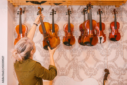 Luthier hanging violins in front of wall at store photo