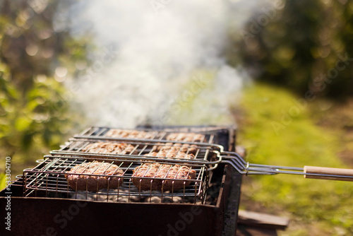 Delicious grilled meat in barbecue grilling basket at backyard photo