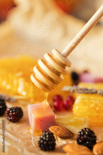 Almonds, blackberries, cheese and honey dripping from honey dipper