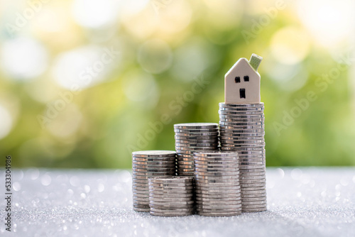 The house model is placed on the coin at the highest point. Investing in real estate business for profit or a loan for a home purchase concept.