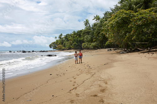 Couple walking on the tropical beach in Corcovado national park, Costa Rica. photo