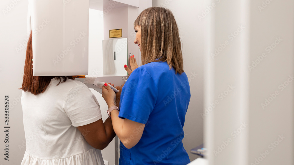 Obraz premium A dentist woman setting up the cbct scanner for one of their clients at the dental clinic