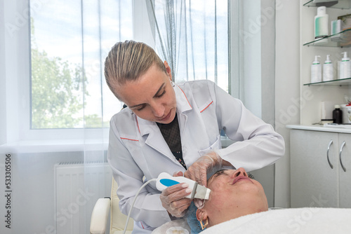 cosmetologist who performs darsonvalization of the skin of the face skin and body photo