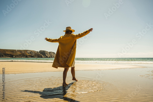 Mature woman with arms outstretched enjoying vacations at beach photo