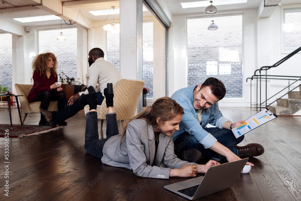 © Westend61 - Businessman and woman working together in modern office sitting on floor