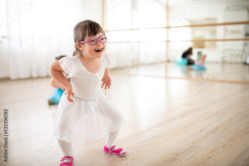 Little girl with down syndrome at ballet class in dance studio. Concept of integration and education of disabled children.