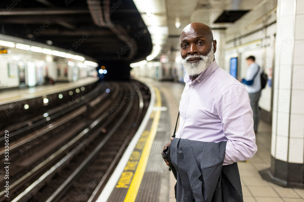 Smiling senior businessman waiting at subway station