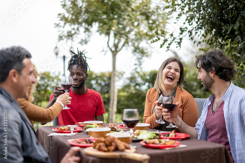Happy people having good times while eating food and drinking wine in the garden  diversity and mixed age range concept