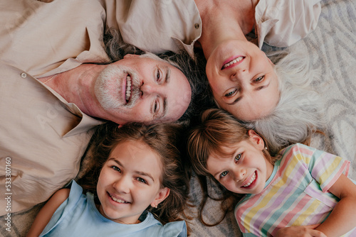 Happy grandparents and granddaughters lying together with heads in circle at home photo