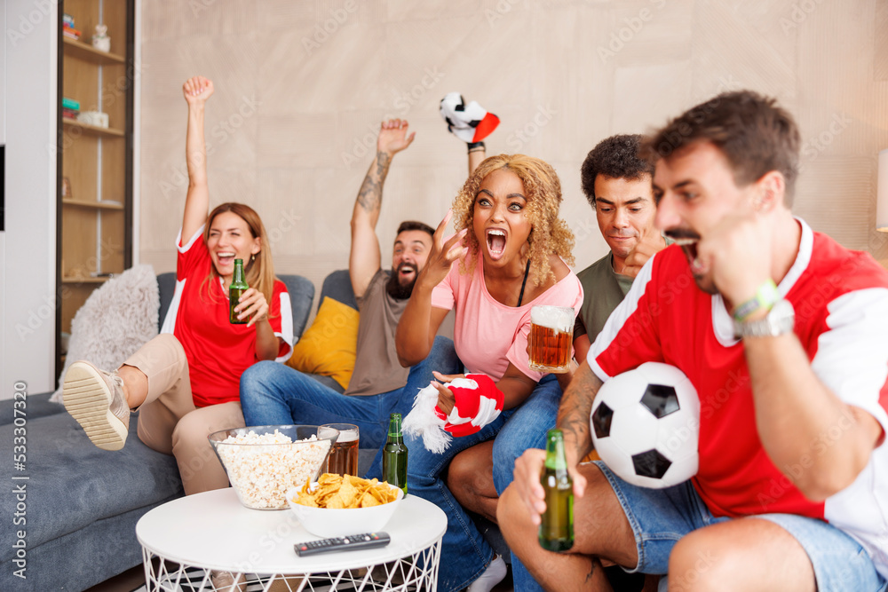 Football fans cheering while watching the game on TV at home