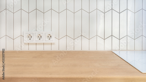 View of kitchen wood countertop and white chevron tiles. Built-in socket. Minimalistic Scandinavian design. Free empty space work surface and hob.surface.