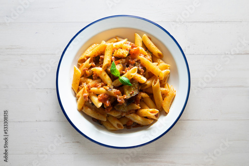 Pasta alla normal - Italian pasta with eggplant, tomato sauce and Parmesan cheese on dark background. Top view. Healthy food.