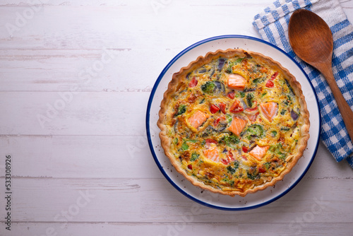 Salmon and vegetable quiche. Traditional French recipe with fish and fresh vegetables with handmade dough and egg.