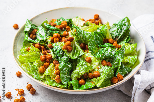 Vegan caesar salad with fried spicy chickpeas in a gray bowl.