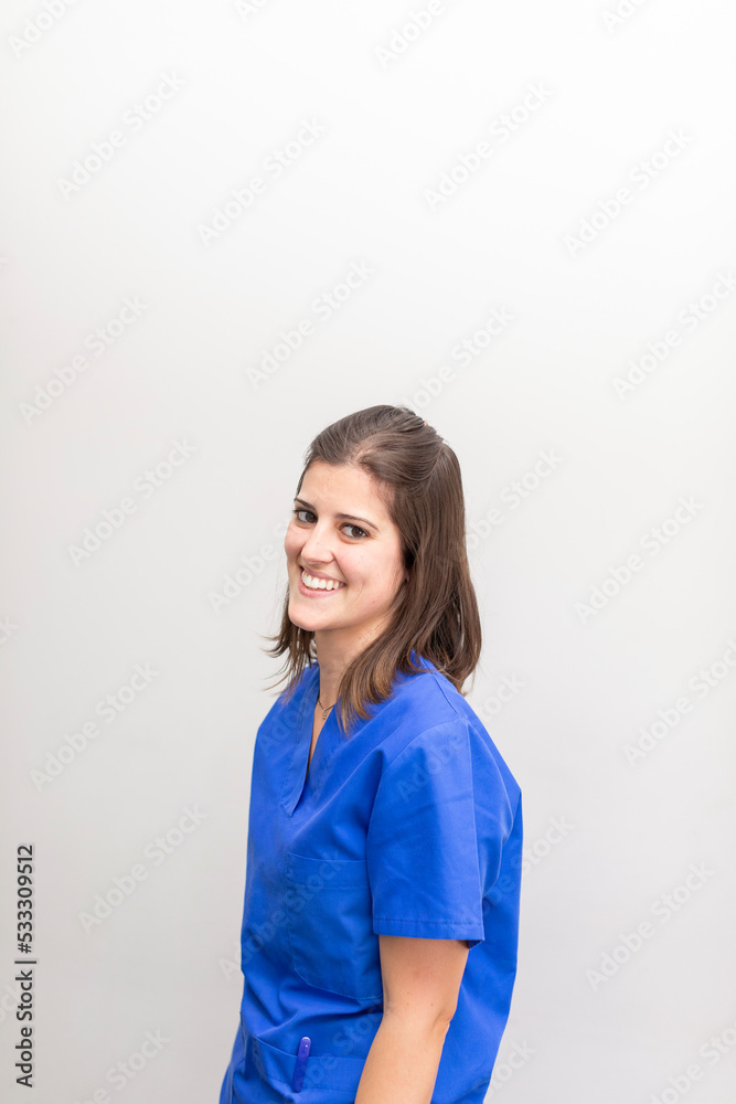 Portrait of a caucasian woman dentist, smiling with joy and looking at camera wearing blue uniform at the dental clinic Portrait of a caucasian woman dentist, smiling with joy and looking at camera wearing blue uniform at the dental clinic