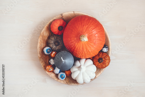 Sustainable Halloween. Eco-Friendly Halloween, plastic free trick-or-treating, Green Halloween. Zero waste Halloween decoration pumpkin, foil candy in wooden plate on table