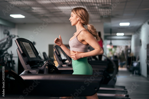 Caucasian woman running on treadmill at fitness center