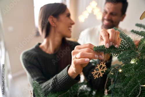 Happy couple decorating Christmas tree at home