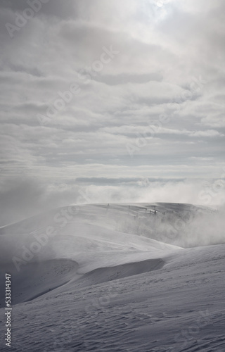 Mountain range covered with snow. Sun and wind over a snow-covered mountainside.