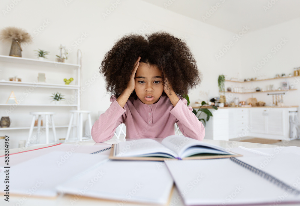 Overwhelmed african american school girl doing homework, feeling down Overwhelmed african american school girl doing homework, feeling down