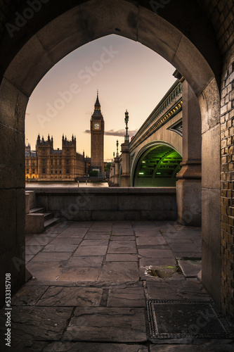 Fotografia Big Ben and the Houses of Parliament, framed by an ancient, stone archway, acros