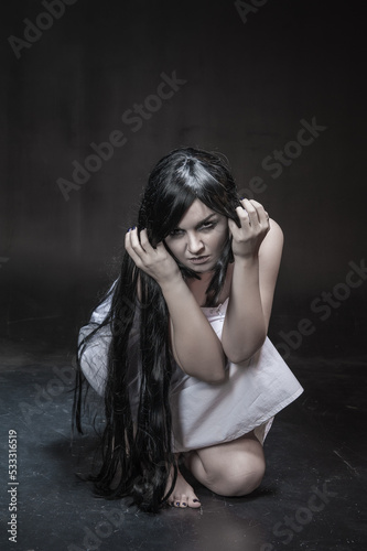 Crazy woman with black long hair on dark background