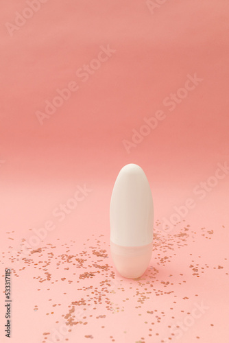 Roller deodorant in a white bottle on a pink background