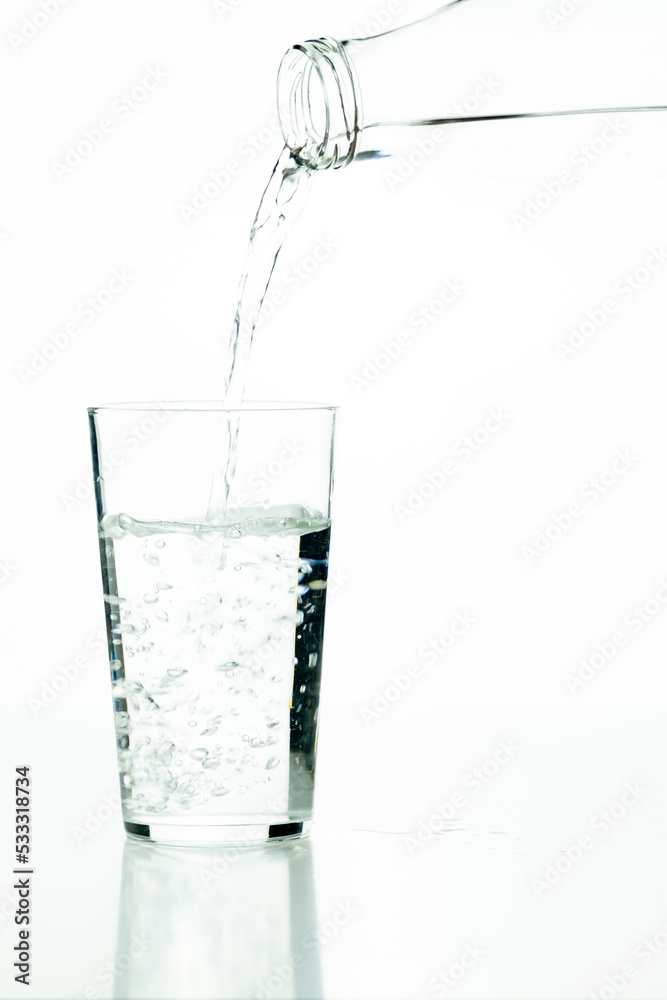 Detail of a glass bottle pouring water into a glass tumbler on a white background. Detail of a glass bottle pouring water into a glass tumbler on a white background.