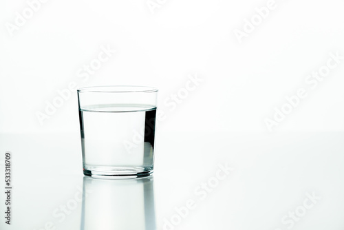 Glass tumbler filled with water on a white background with a minimalist concept and plenty of copy space.