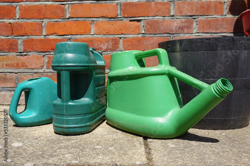 gardening watering cans on patio. plastic watering jugs in garden 