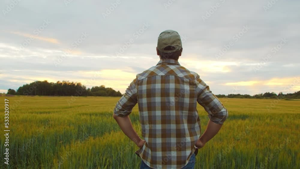 Farmer in front of a sunset agricultural landscape. Man in a countryside field. Country life, food production, farming and country lifestyle concept. Farmer in front of a sunset agricultural landscape. Man in a countryside field. Country life, food production, farming and country lifestyle concept.