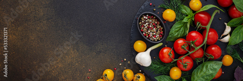 Food banner  fresh ripe red and yellow tomatoes  spices and basil leaves  garlic and green onions on dark board  healthy food concept  copy space  top view
