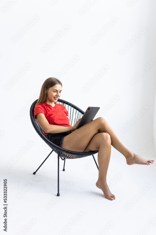 People, technology and communication concept. Portrait of smiling young woman with digital tablet sitting in armchair, working online People, technology and communication concept. Portrait of smiling young woman with digital tablet sitting in armchair, working online