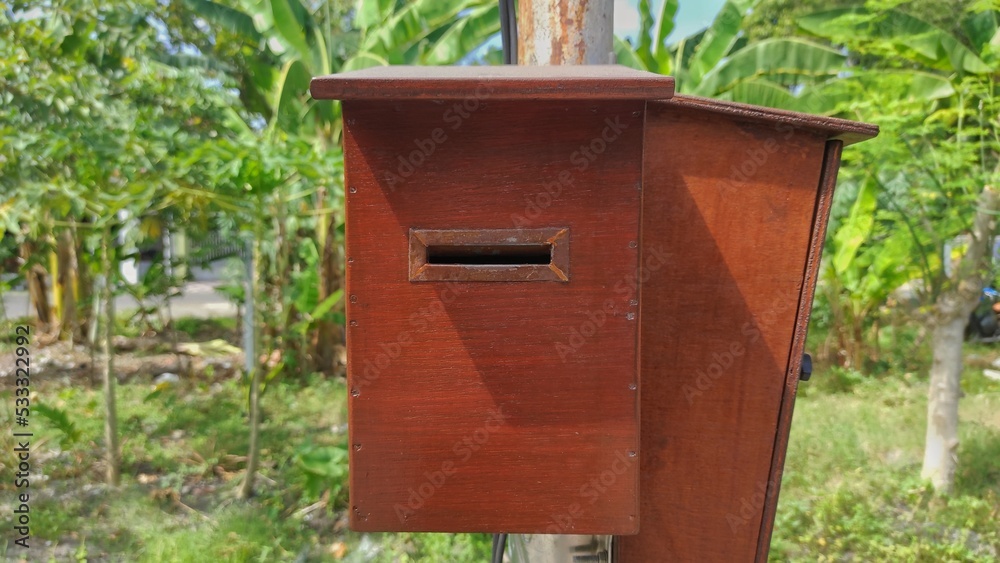 Object background of wooden mailbox on the pole near by garden of the house Object background of wooden mailbox on the pole near by garden of the house