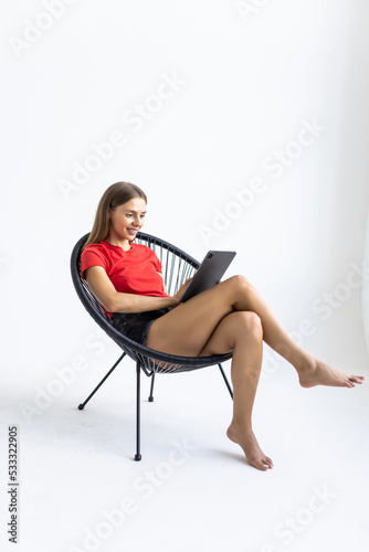 People, technology and communication concept. Portrait of smiling young woman with digital tablet sitting in armchair, working online