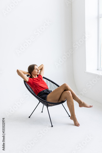 Young calm woman resting in rocking chair at home