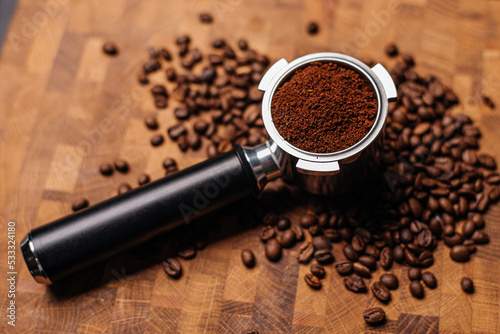 Portafilter with ground coffee on the background of coffee beans