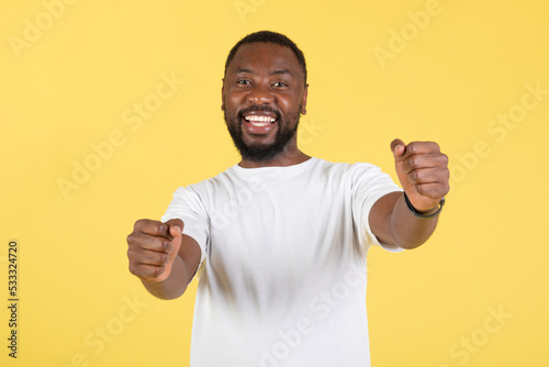 African Guy Holding Invisible Wheel Pretending Driving Car, Yellow Background