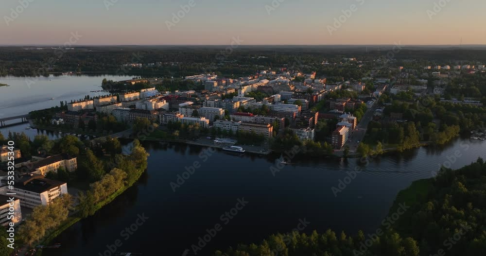 Aerial view of a boat passing the cityscape, driving in tranquil waters of lake Vanajavesi, summer sunset in Hameenlinna, Finland Aerial view of a boat passing the cityscape, driving in tranquil waters of lake Vanajavesi, summer sunset in Hameenlinna, Finland