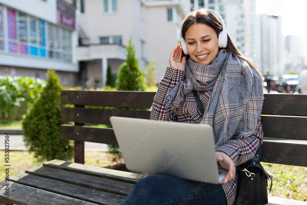 young woman on video chat with laptop and earphone with a smile on her face, the concept of remote work young woman on video chat with laptop and earphone with a smile on her face, the concept of remote work