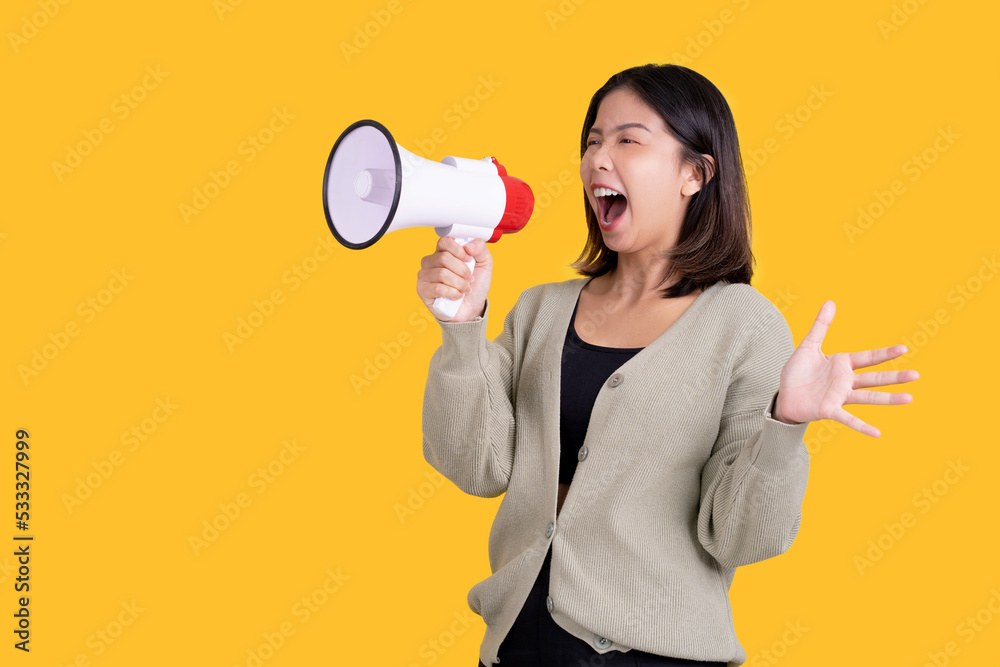 Asian woman screaming in a megaphone spreading her hands looking away on a bright yellow background. Asian woman screaming in a megaphone spreading her hands looking away on a bright yellow background.