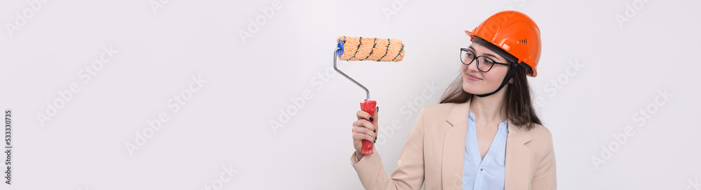 Girl engineer in an orange construction helmet with plastering painting tools in her hands on a white background. Girl engineer in an orange construction helmet with plastering painting tools in her hands on a white background.