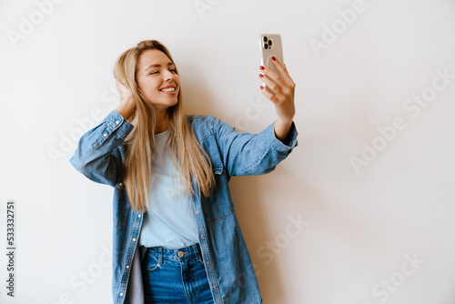 White blonde woman smiling while taking selfie on mobile phone