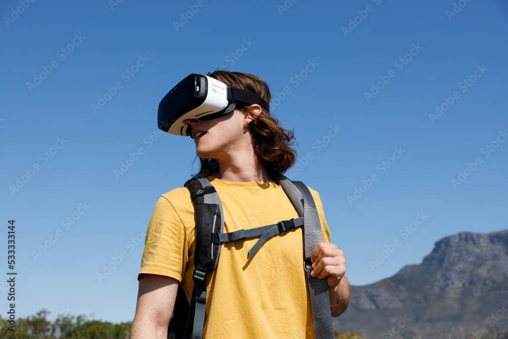 Happy adventuring male wearing vr headset augmented reality virtual reality in beautiful mountain landscape concept. Young woman using virtual reality glasses stands on a cliff on top of a mountain