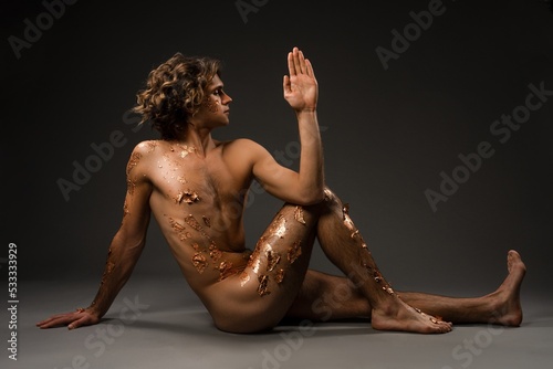Naked young man doing Seated Spinal Twist pose photo