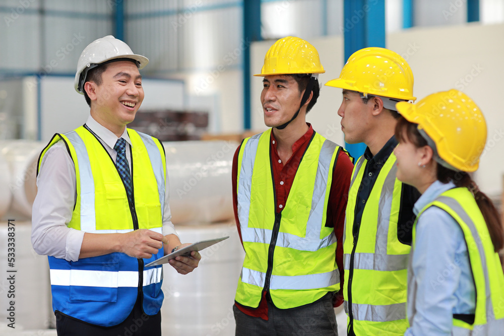 Group of technician engineer and businessman in protective uniform standing and discussing, researching, brainstorming and planning work together with tablet at industry manufacturing factory Group of technician engineer and businessman in protective uniform standing and discussing, researching, brainstorming and planning work together with tablet at industry manufacturing factory